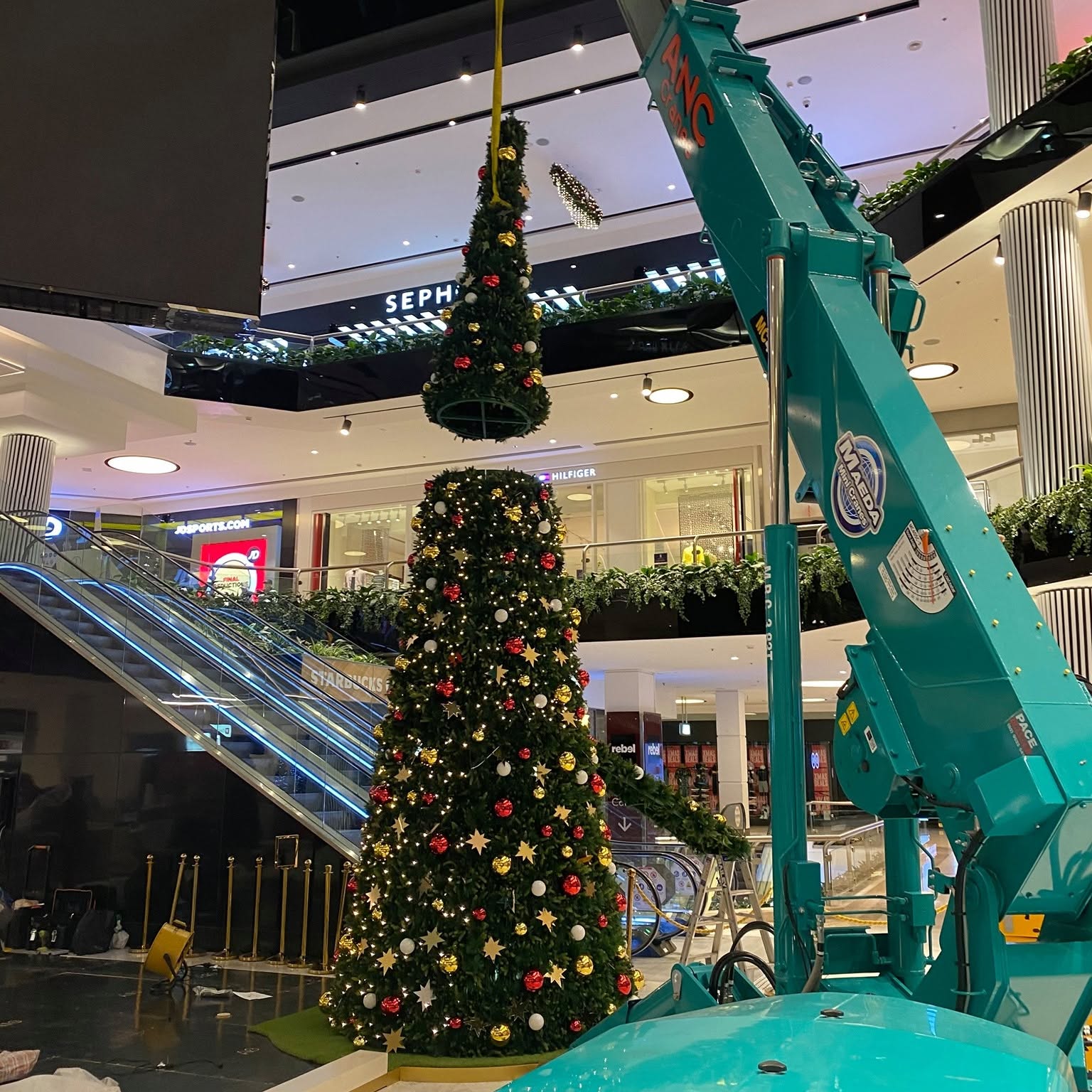 Mini crane installing a Christmas tree display inside a shopping centre