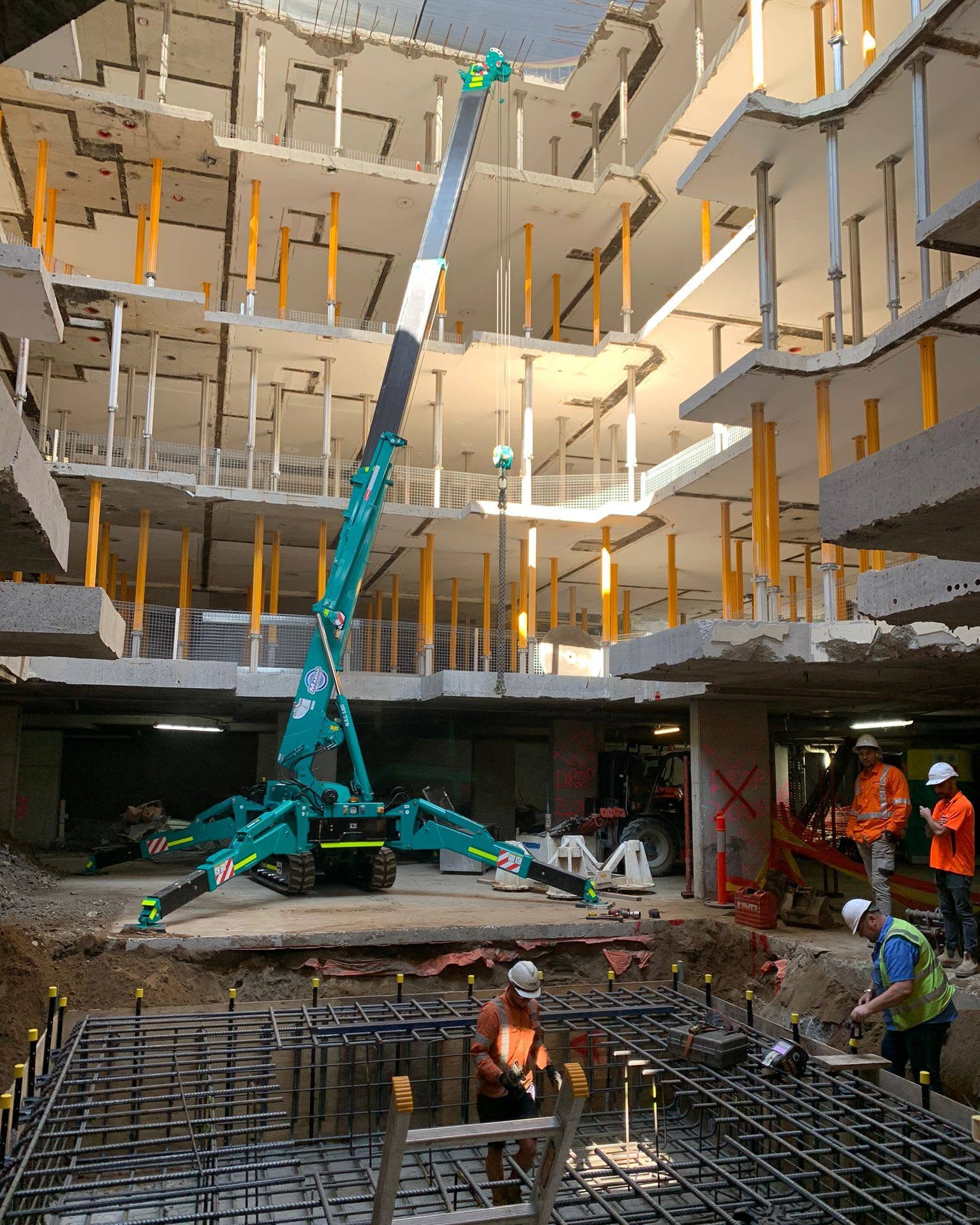 Mini crane lifting inside a multi-level construction atrium