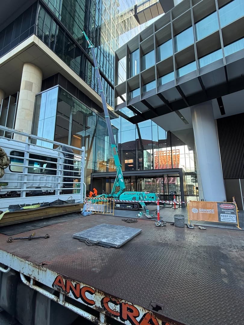 Mini crane working near a commercial facade in a city access zone
