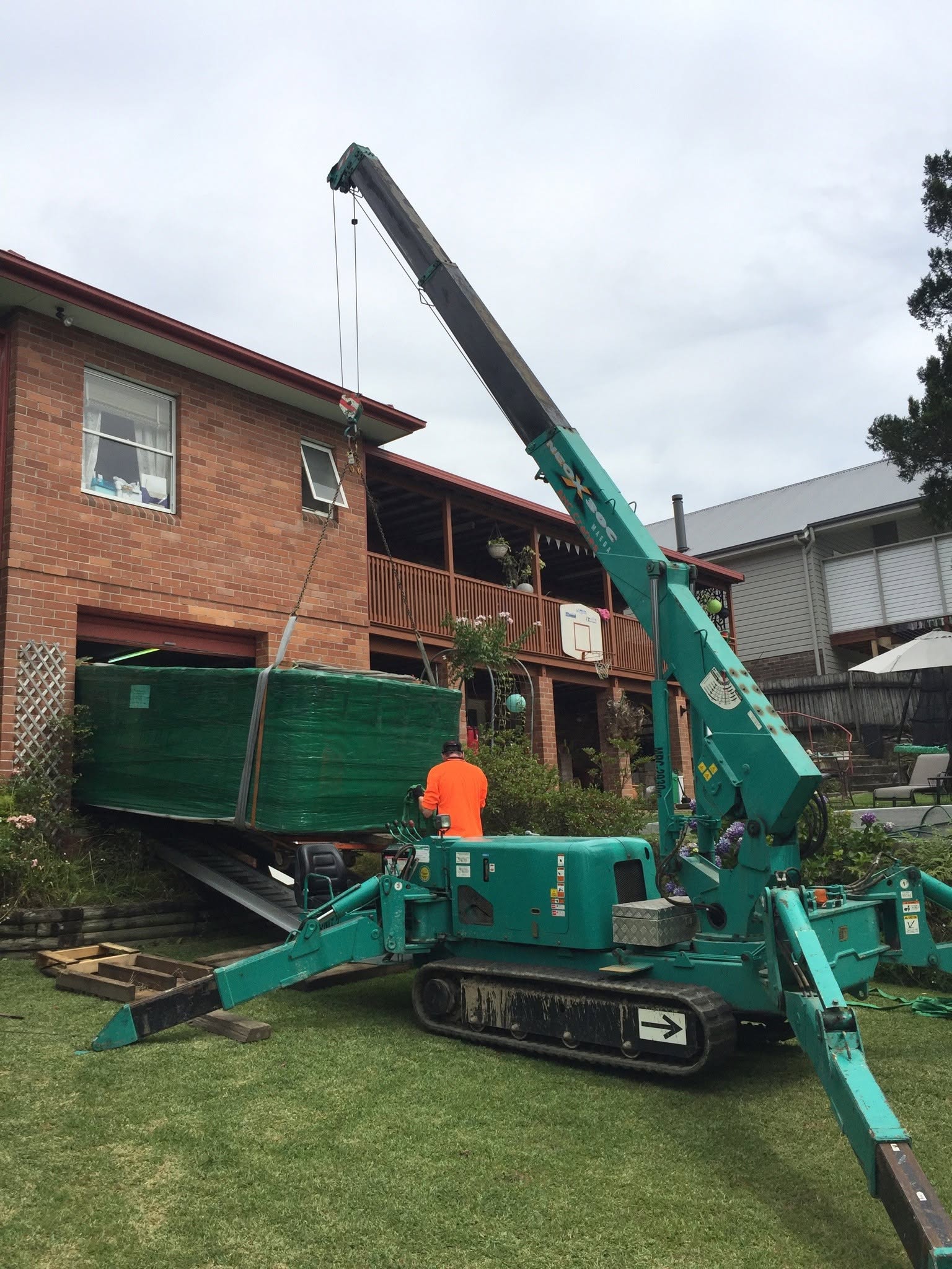 Mini crane lifting a spa at a residential property